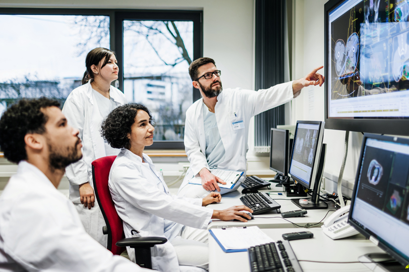 Foto de cientistas reunidos olhando para exames de imagem cerebral